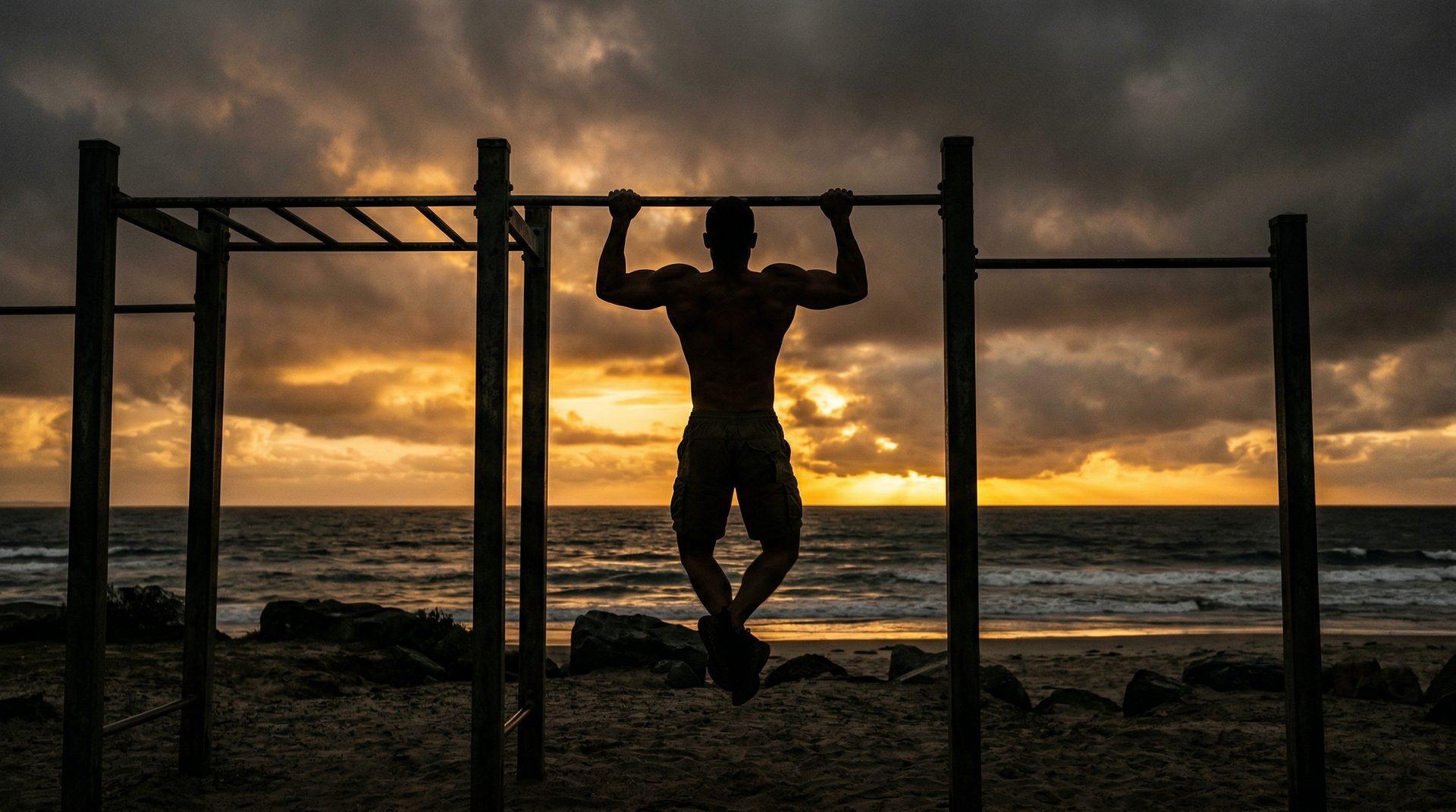 Silhouette of a man doing chin-ups at a beach park during sunrise